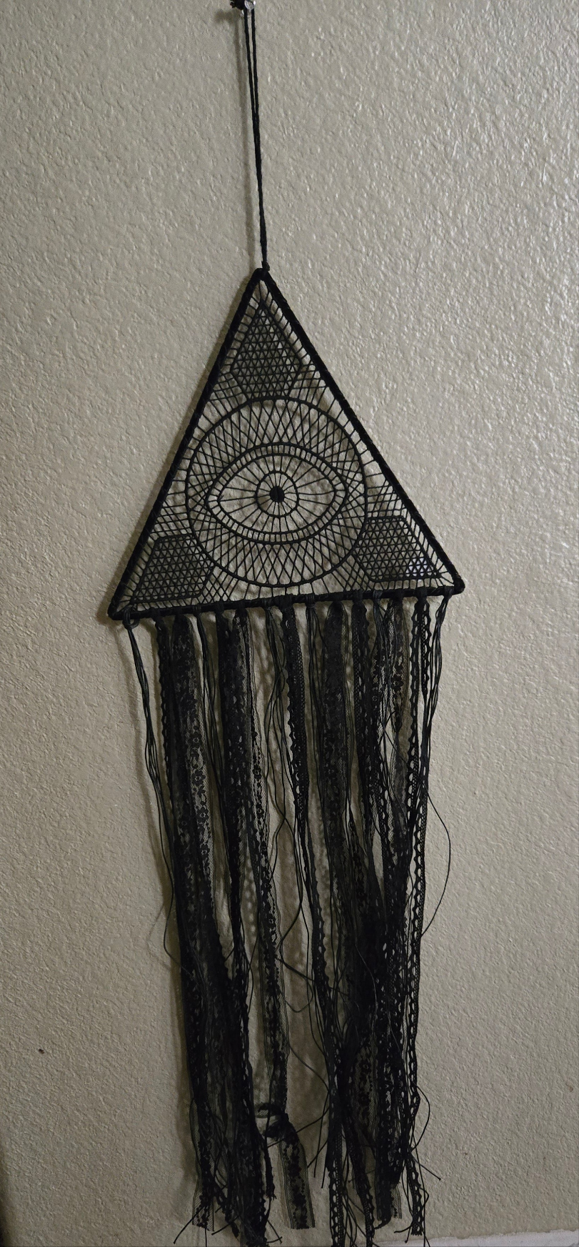Black triangular wall hanging with eye design