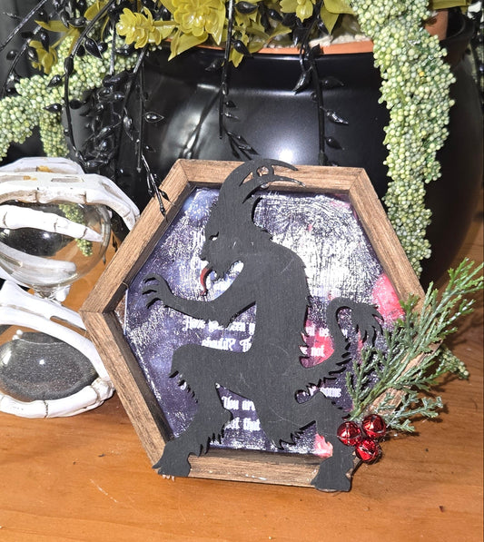 Decorative wreath with greenery and a small house ornament on a wooden surface.