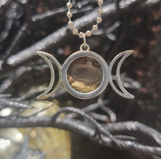 Chrome triple moon travel protection charm with spelled herbs and crystals in the middle