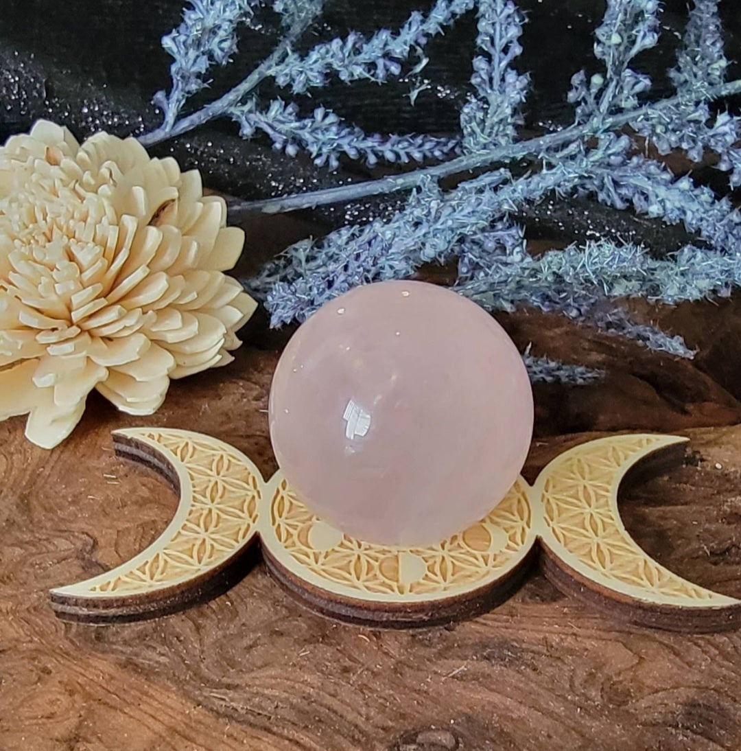Rose quartz crystal sphere on a wooden triple bone spear holder