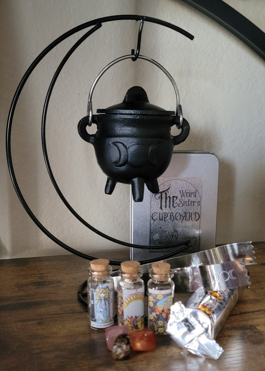 Three inch casr iron cauldron, with the triple moon design being held by a metal Crescent moon, stand with tarot Spell bottle jars, charcoal discs blacksand to complete this bulcket